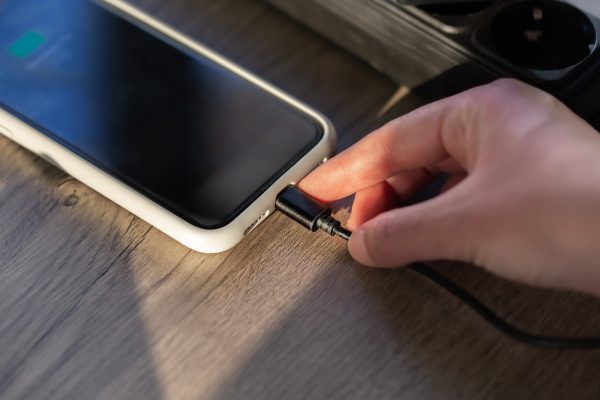 Connecting a magnetic cable to a smartphone for charging, close-up.